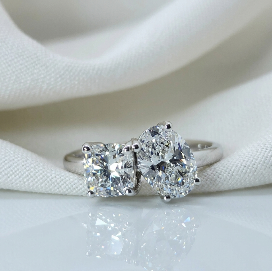 Diamond ring with heart and square-shaped gemstones on a white fabric background